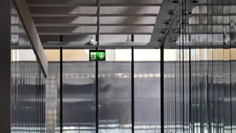 Emergency exit sign illuminates long modern glass corridor inside contempor.. Stock Footage 332202454