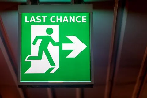 The emergency exit sign indicates the direction of way to last chance. Stock Photos