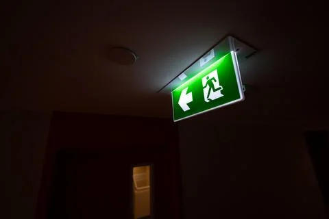 An emergency fire exit light box with arrow hangs from a hospital ceiling, .. Stock Photos