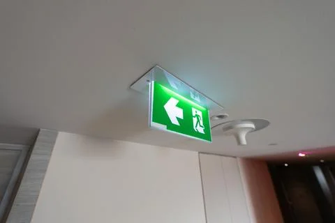 An emergency fire exit light box with arrow hangs from a hospital ceiling, .. Stock Photos