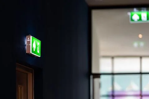 An emergency fire exit light box with arrow hangs from a hospital ceiling, .. Foto stock