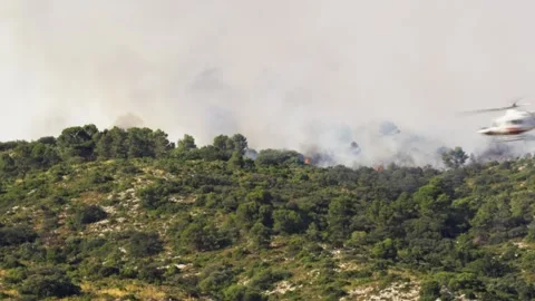 Emergency helicopter flies quickly over forest fire in Spain Stock Footage 314873448