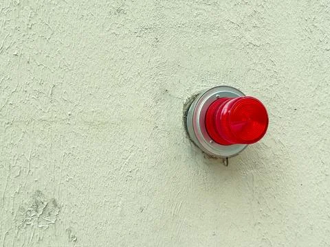 Emergency light mounted on a wall shining bright red in a commercial buildi.. Stock Photos