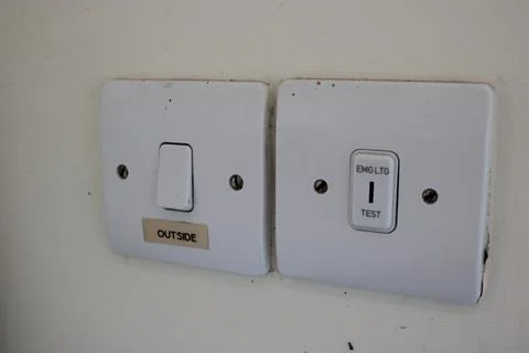 Emergency lighting testing switch and a regular light switch with label outside Stock Photos