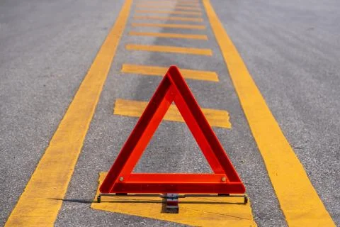 Emergency red warning triangle on the road sign with yellow traffic line Stock Photos