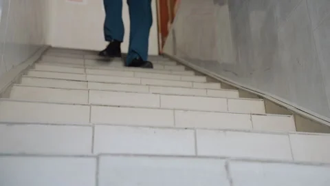 Emergency responder ascent. Ambulance worker carefully navigates worn stairs 库存影片 337547985