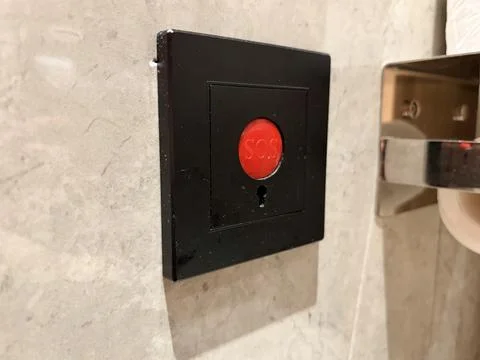 Emergency SOS button on a beige wall. 스톡 사진