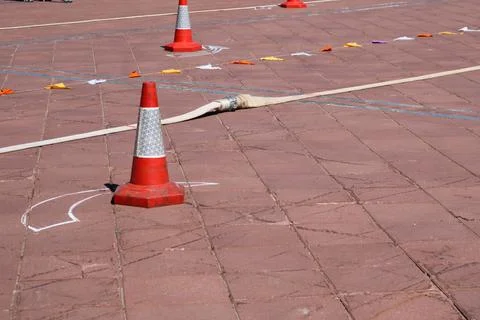 An emergency triangular orange cone denoting danger and a fire hose lie on th Stock Photos