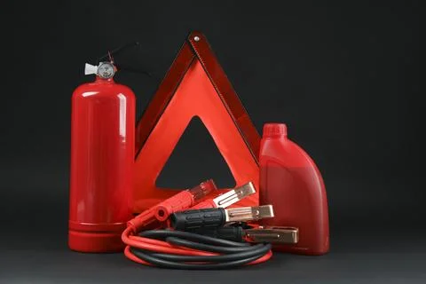 Emergency warning triangle, red fire extinguisher, battery jumper cables an.. Stock Photos