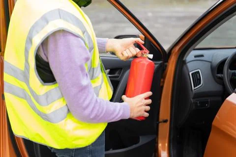 An emergency worker demonstrates how to use a fire extinguisher in the car Foto stock