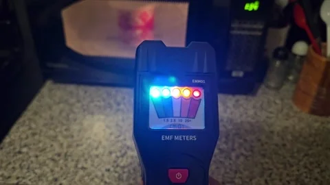 EMF meter measuring microwave oven as person goes near and far from oven. Video stock 261625424