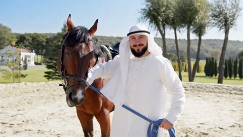 Emirates man with traditional clothes walking his horse in the desert. Arabian Stock Footage 317063089