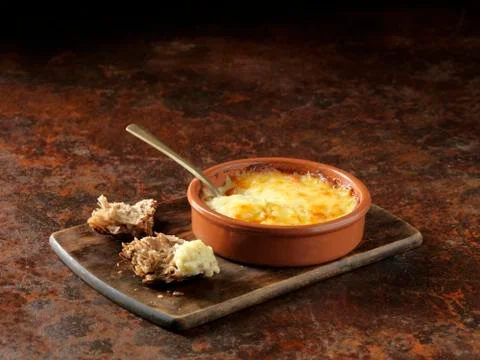 Emmental, Gruyere and Calvados cheese baked in terracotta dish and torn rustic Stock Photos