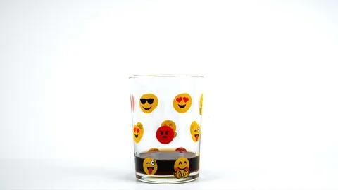 Emoji patterned glass cup is filled with soda on white background Stock Footage 129324515