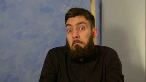 Emotion. I do not know. A man with a beard in a dark shirt shrugs 스톡 동영상 123824506