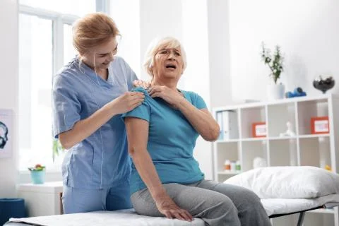 Emotional aged woman feeling pain in the shoulder Stock Photos