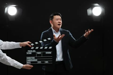 Emotional asian actor performing while second assistant camera holding clap.. Stock Photos
