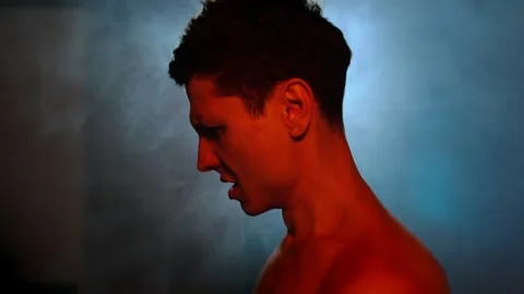 Emotional breakdown and inner conflict. Man in profile lit with red and blue Stock Footage 311987331