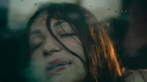 Emotional expression captured through glass in a dimly lit urban setting Stock Footage 296022178