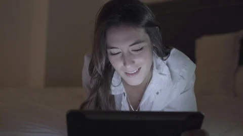 Emotional girl using tablet pc in bedroom at night Stock-Footage 100550198