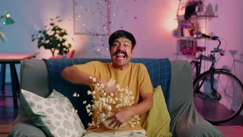 Emotional Hispanic guy sitting in front of TV watching football eating popcorn Stock Footage 116741499