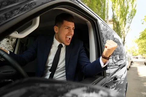 Emotional man yelling in car. Aggressive driving behavior Stock Photos