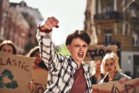 Emotional young woman screaming a slogan and leading a group of demonstrators on Stock Photos