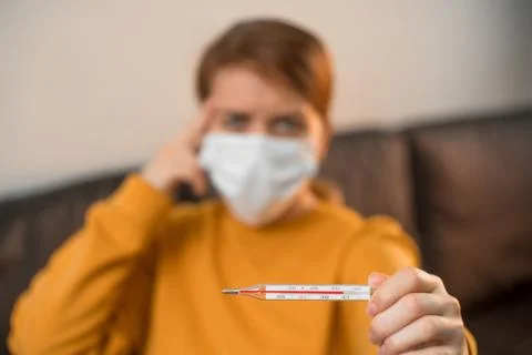 Emphasis on a thermometer for measuring temperature, sick young girl sitting  Stock Photos