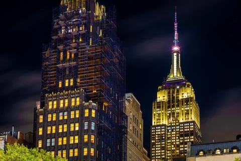 Empire State Building night view framed by tall Manhattan city buildings Fotos de archivo
