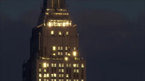 Empire State Building reflects setting sun against dark, moody sky. Stock Footage 78805124