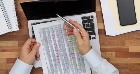 Employee compares data on paper spreadsheet and on laptop Stock Footage 267811507