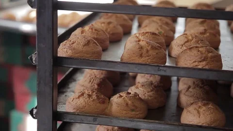 Employee devastates rows with ruddy pastries in bakeryshop indoors. Stock Footage 77578464