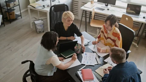 Employee with Disability Working with Colleagues Ananlyzing Documents in Office Stock Footage 335756461