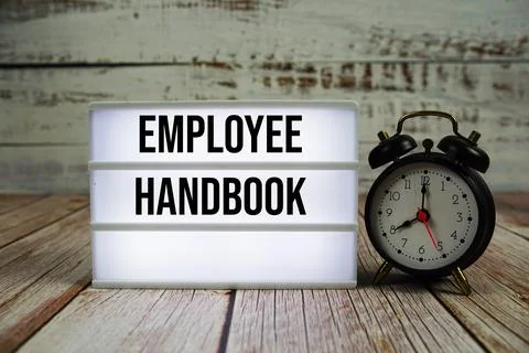 Employee Handbook text on light box with alarm clock on wooden background 스톡 사진