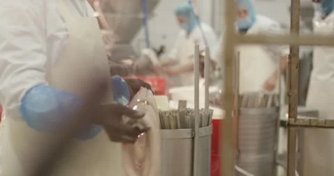 Employee loading fresh sausage strands onto steel hanging rod, Wide Shot Видео 340015121