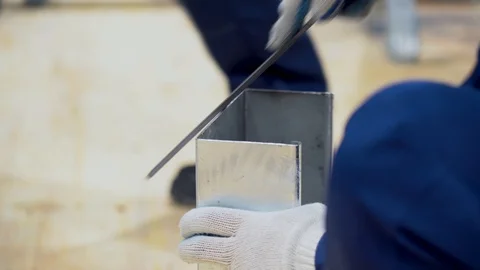 Employee man uses a file, aligns, grinds sharp edges of tin metal gutter closeup Stock Footage 126356661