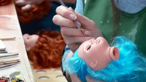 An employee picks up the head of a plastic blank of a baby doll and applies Stockbeeldmateriaal 168282915