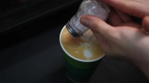 Employee pours cinnamon to make pattern on foam of coffee Stock Footage 144063561