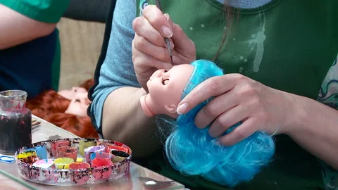 An employee puts makeup on the head of a plastic blank of a baby doll Video stock 168283336