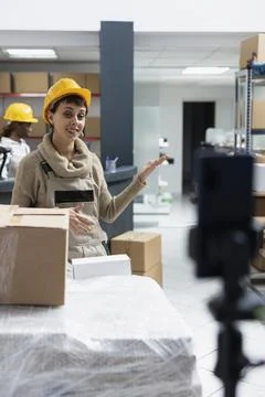 Employee recording a live tutorial in an industrial warehouse Foto stock