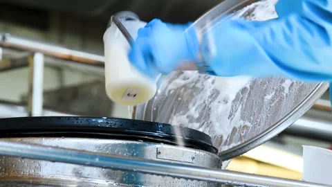 An employee takes a sample of milk for quality control and testing in an in.. Vídeos de archivo 329870580