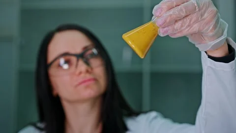 An employee of a technical laboratory holds a test tube with paint in her Stock Footage 239859700
