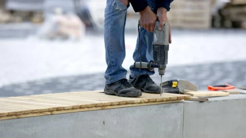 Employee in uniform uses drill to construct a bench Stock Footage 246054325