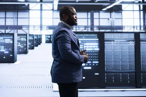 Employee walking through server rows to configure network infrastructure Stock Photos