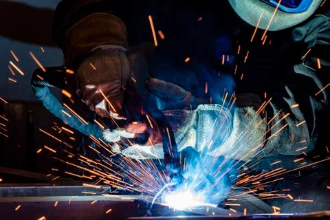 Employee welding steel with sparks using mig mag welder - focus on sparks. Stock Photos