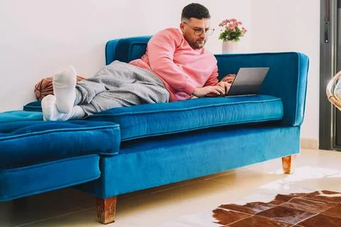 Employee working from the sofa at home with his laptop due to the coronavirus Stock Photos