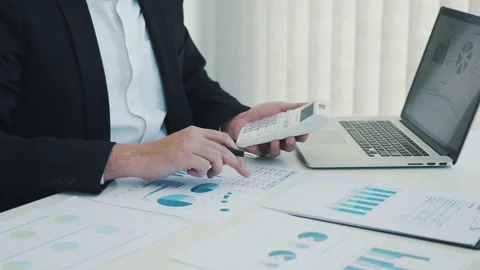 Employees are using a calculator to calculate earnings in a graph displayed on t Stock Footage 149540325