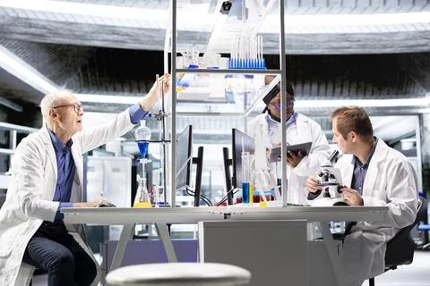 Employees group studying sample tray under the microscope for research study Stock Photos