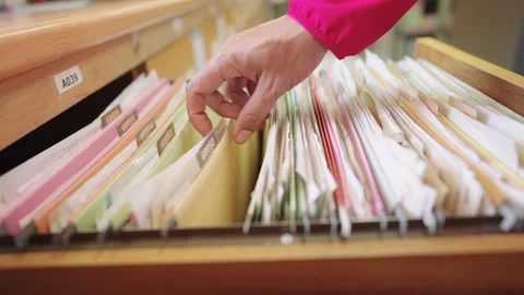 The employee's hand was searching for documents in the filing cabinet. Stock Footage 148101423