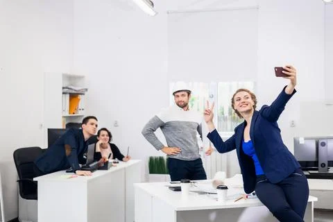 Employees having fun in the office, posing and taking selfies wi Stock Photos